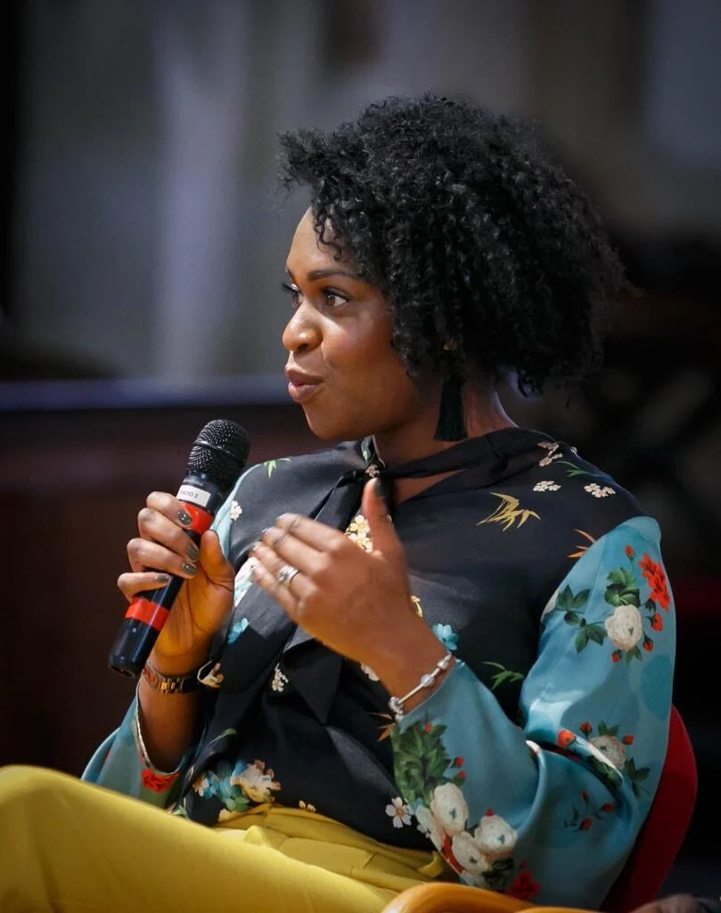 Emma speaking into a microphone while seated.