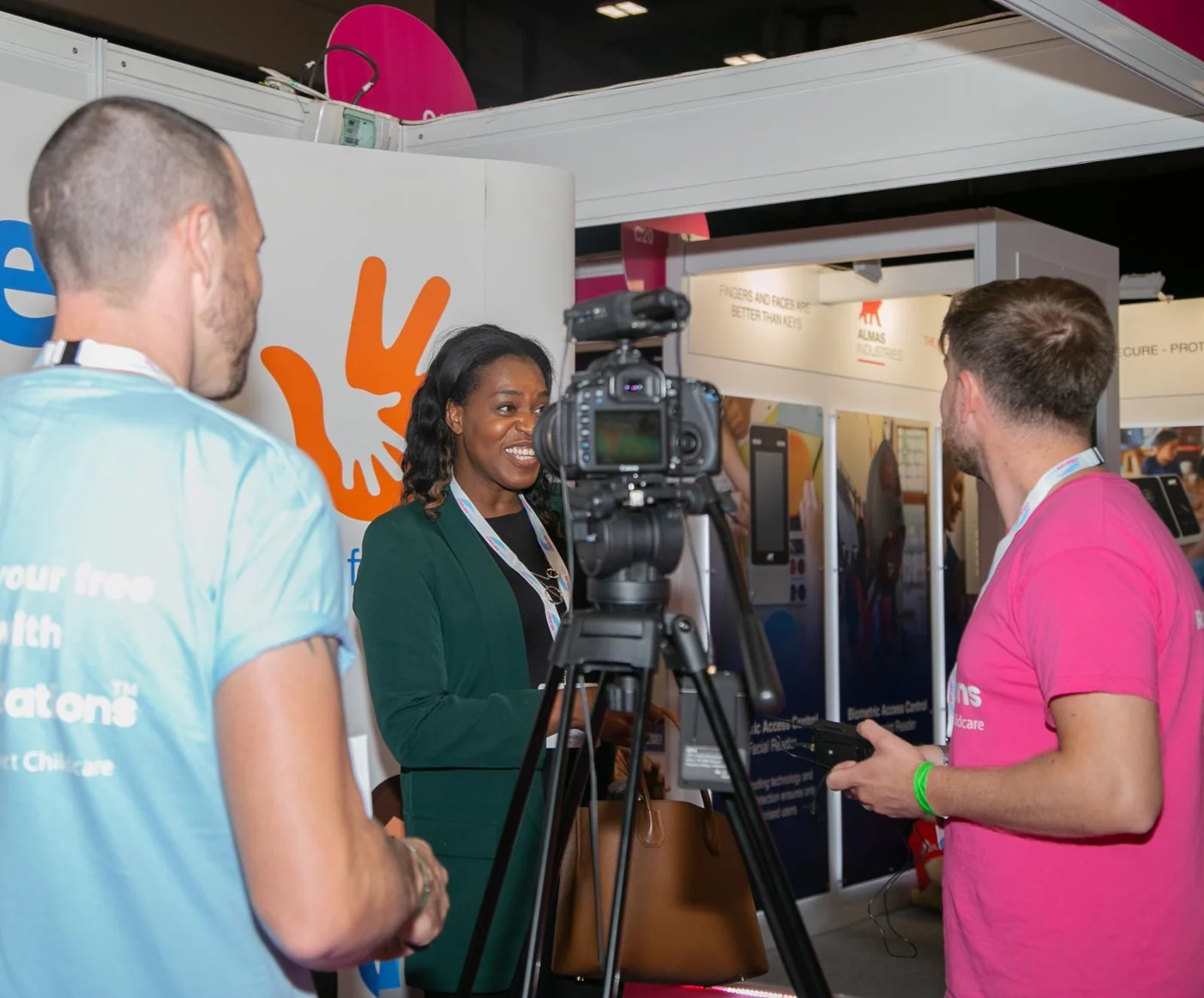 Emma speaking with a filming team beside a camera at an exhibition.