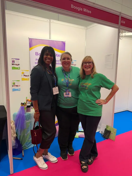 Emma standing with two adults at a Boogie Mites exhibition stand.