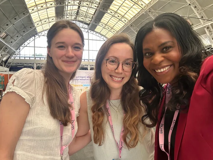 Emma smiling with two adults at an exhibition venue.