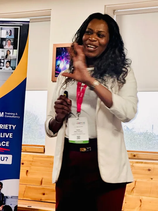 Emma holding a microphone beside presentation banners.