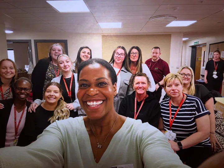 Emma taking a group photograph with adults in a training room.