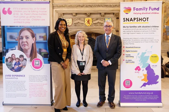 Emma standing with two adults beside Family Fund exhibition banners.