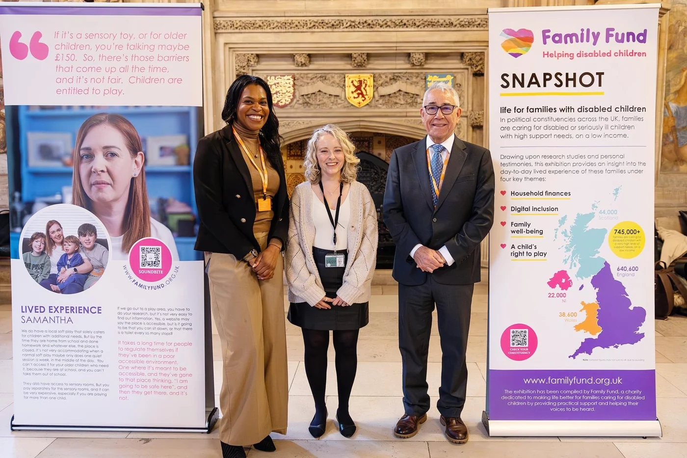 Emma standing with two adults beside Family Fund exhibition banners.