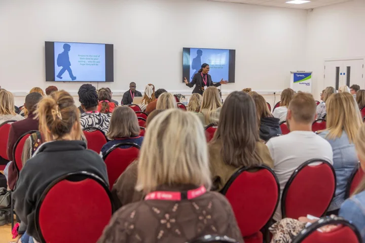 An audience seated facing a speaker and presentation screen.