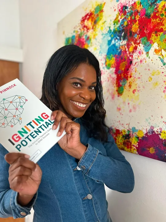 Emma smiling and holding a copy of Igniting Potential.